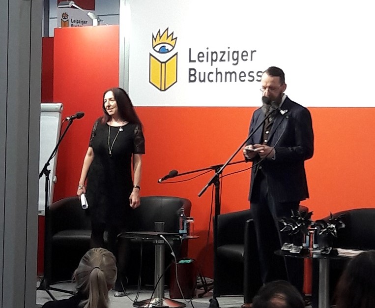 Eine Frau und ein Mann an Mikrofonen, dahinter der Schriftzug "Leipziger Buchmesse"