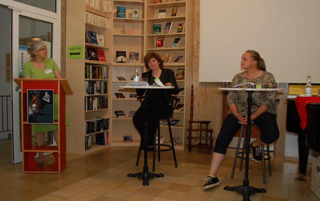 Klaudia Seibel, Maike Braun und Theresa Hannig unterhalten sich vor einem Bücherregal