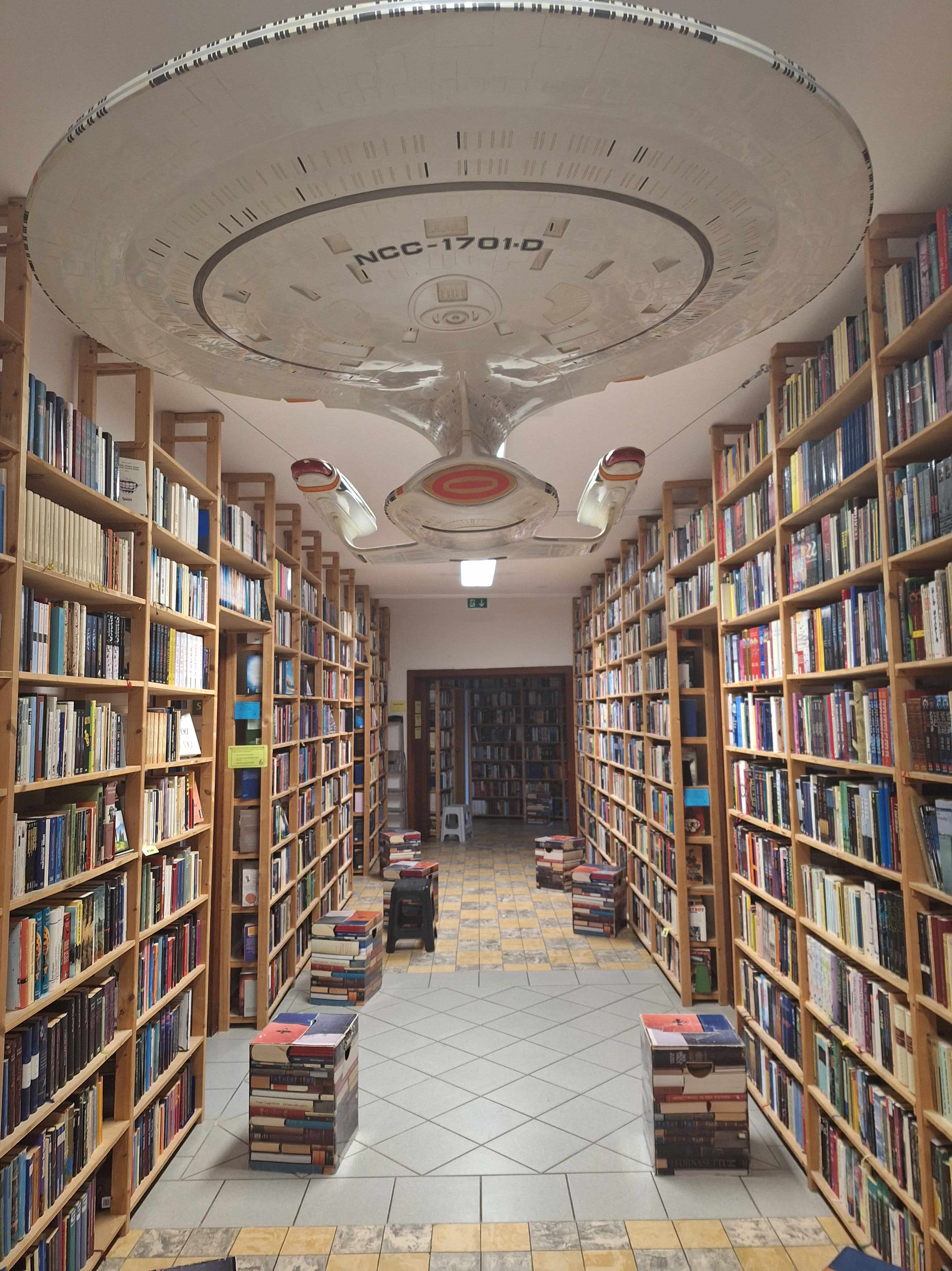 Gang in der Phantastischen Bibliothek Wetzlar mit vielen Büchern und an der Decke einem großen Modell der Enterprise