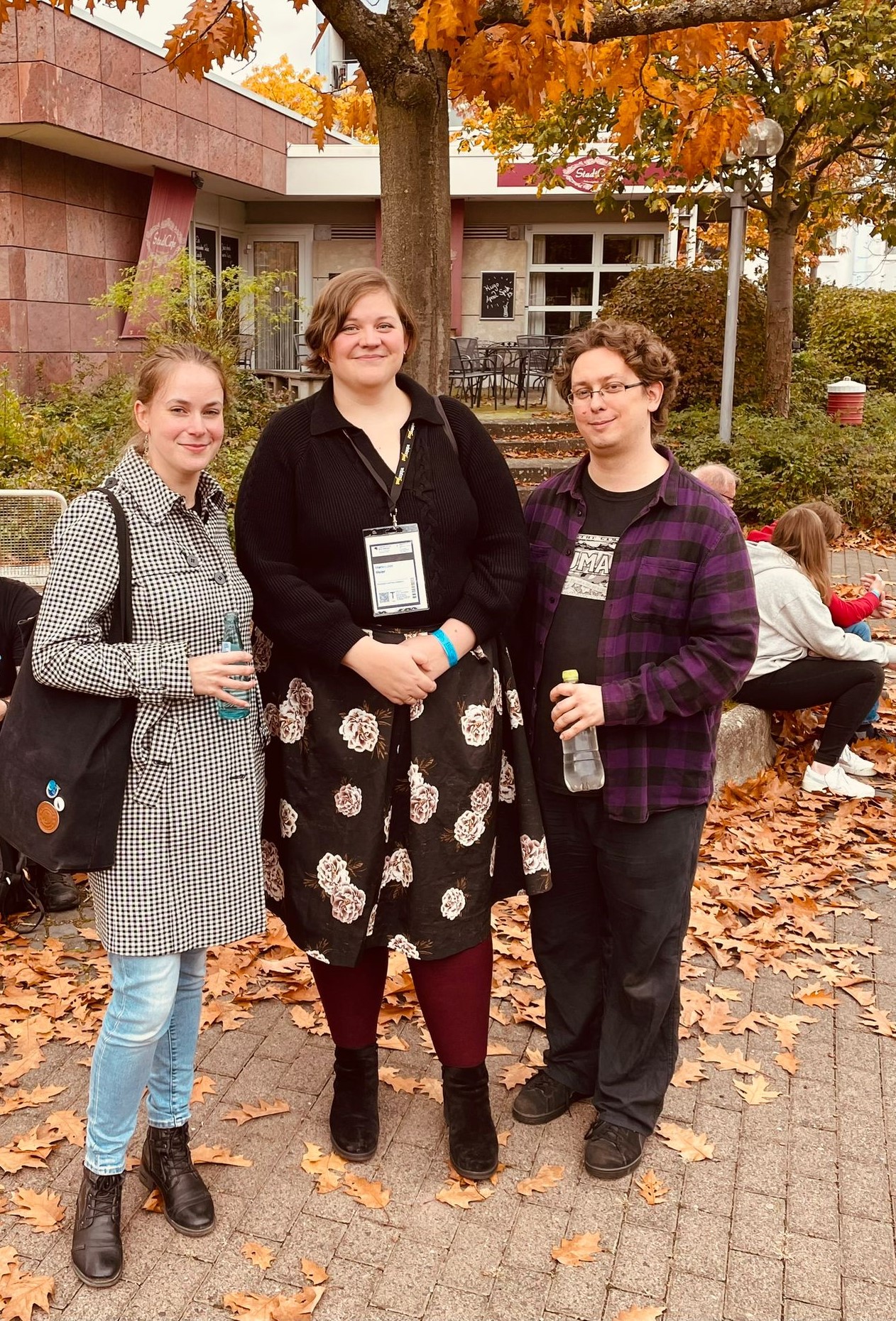 Alessandra Reß (mit Wasserflasche in der Hand), Marie Meier und Tino Falke (auch mit Wasserflasche) stehen vor einem herbstlichen Baum